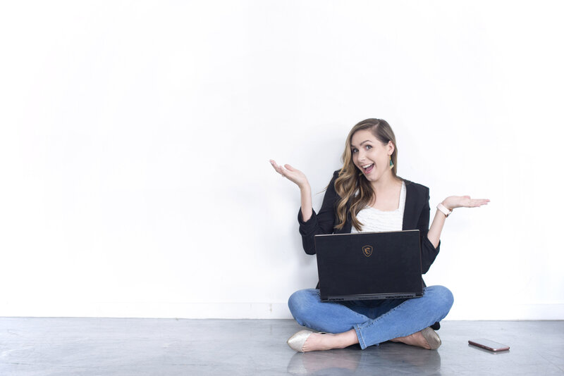Brand image of woman holding laptop against white wall with expressive face