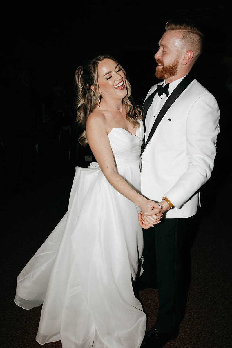 Bride and groom laughing and dancing during their wedding reception, photographed by a Spokane wedding photographer.