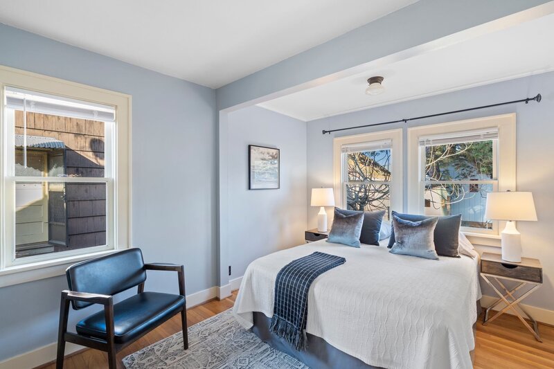 A bedroom featuring a bed in front of large windows.