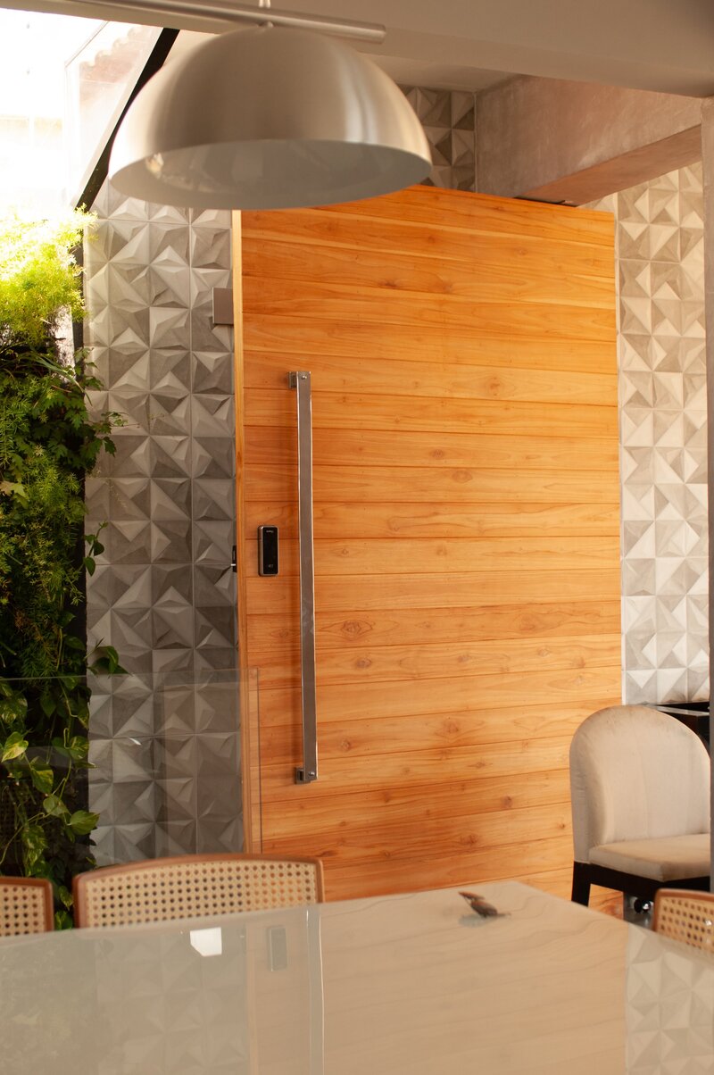 Inspiring modern entryway featuring a wooden pivot door with a steel handle bar.