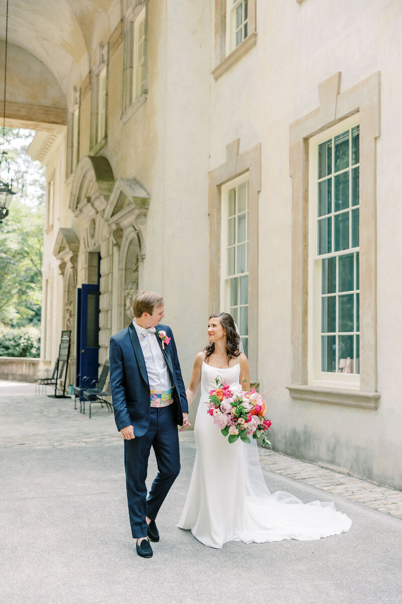 Bride and groom walk hand in hand outside of European Swan House Atlanta History Center
