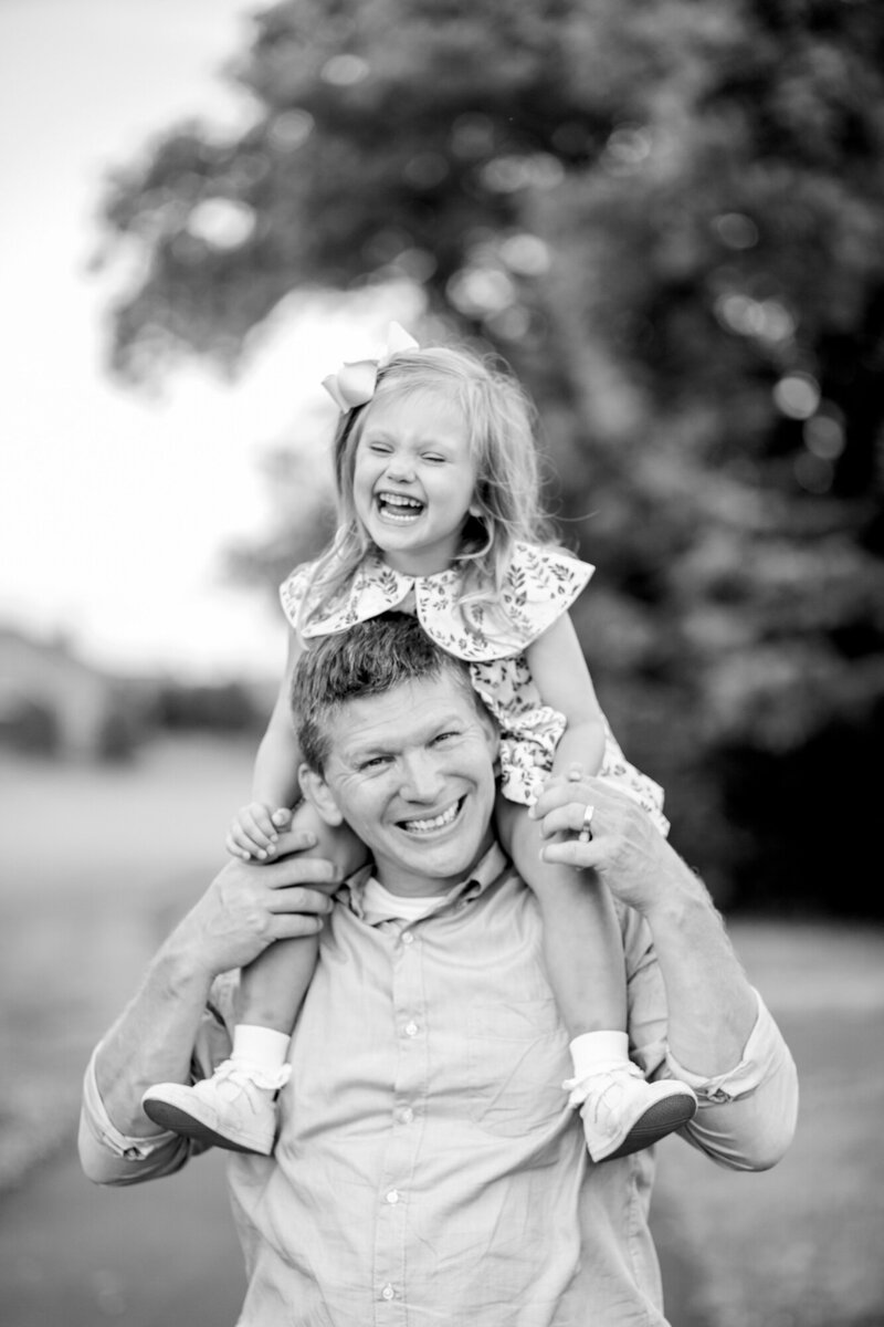 a little girl rides on the shoulders of her dad.