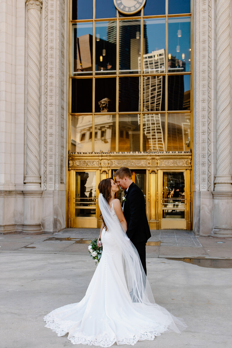 Bride and groom embrace in front of The Wrigley Building