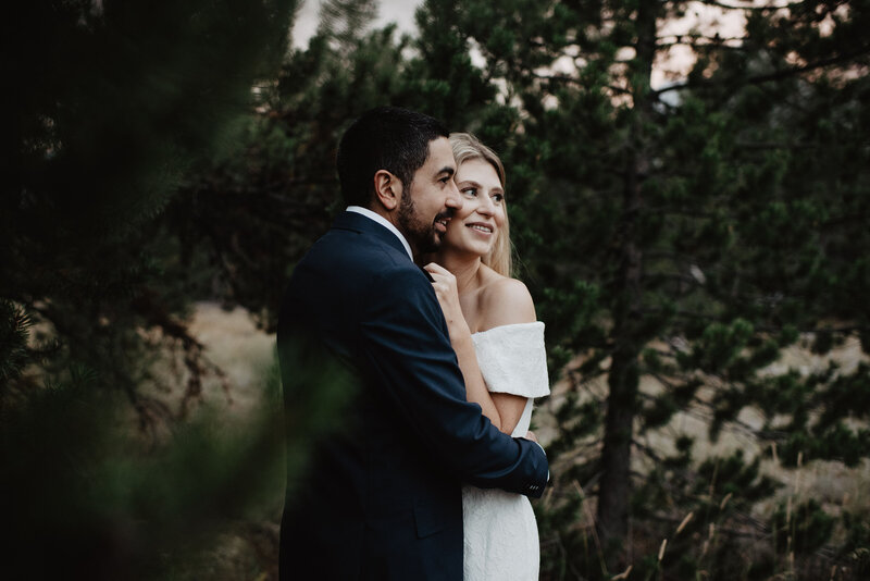 woodland wedding in the grand tetons with bride and groom posing together and smiling in a grove of trees captured by jackson hole wedding  photographers