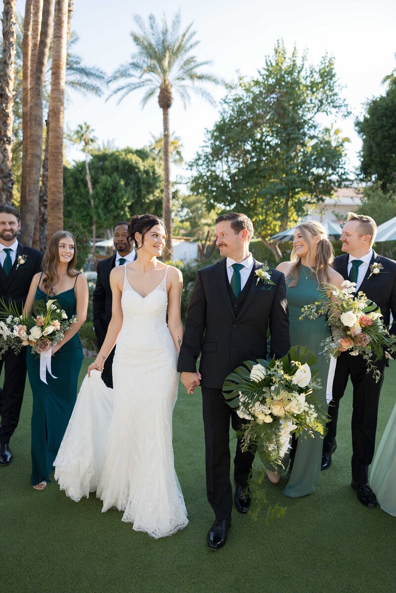Bride and groom walk with wedding party holding hands on at the Scott Resort.