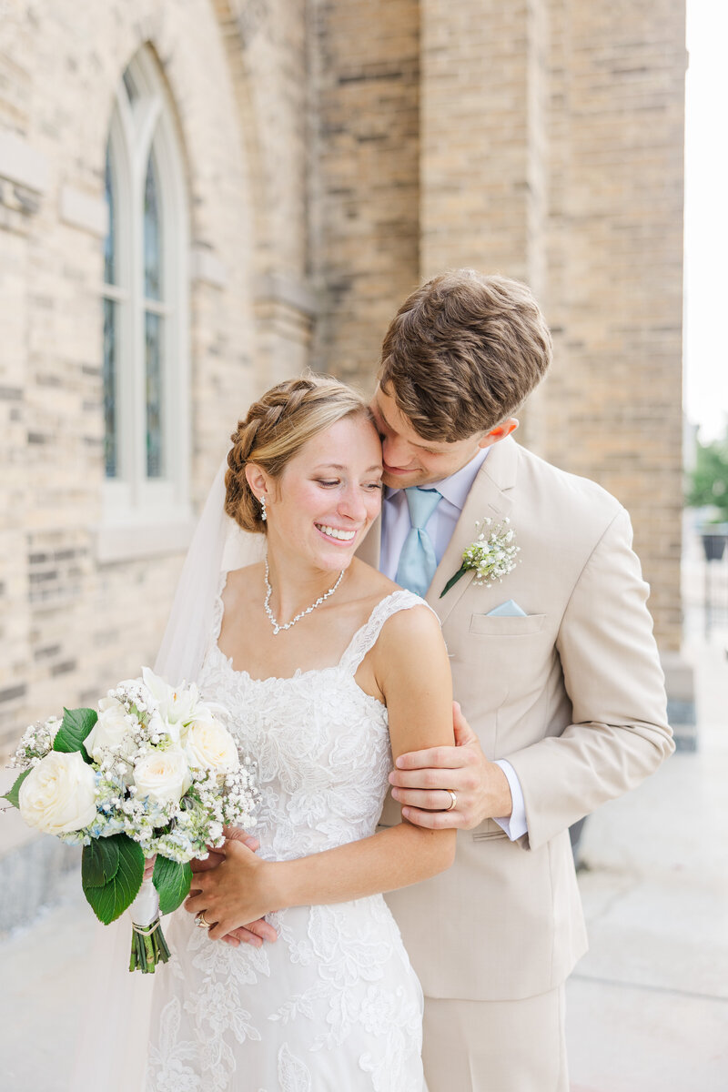bride and groom embracing outside of a church
