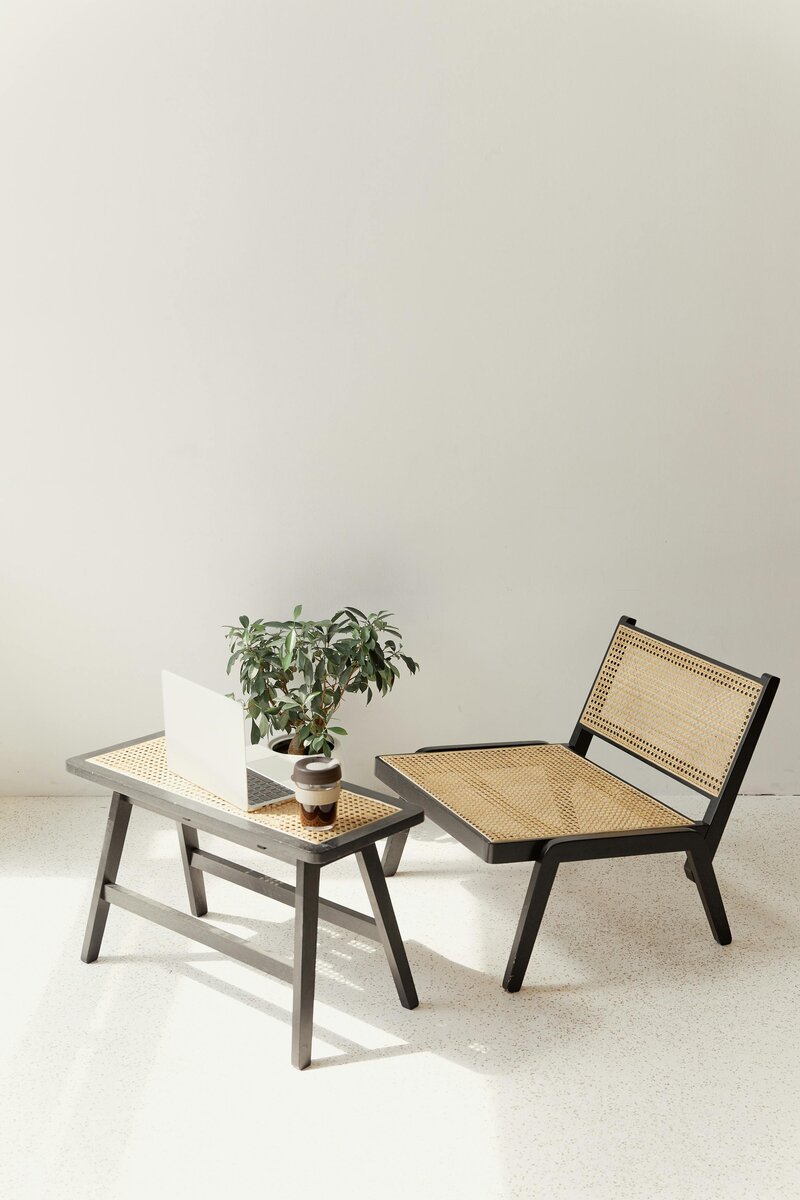 Mini rattan table and chair with a laptop, tea cup, and plant on the table