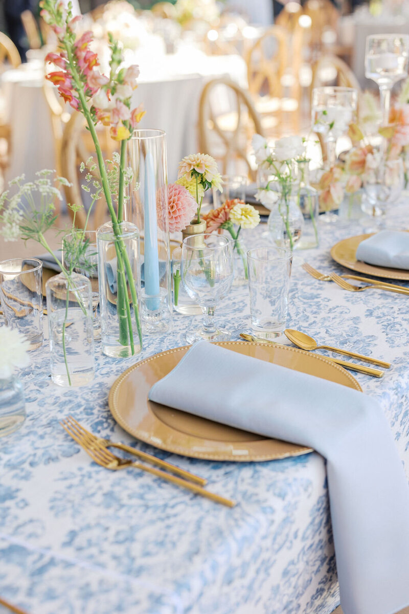Elegant blue and white table at wedding reception with multi colored florals