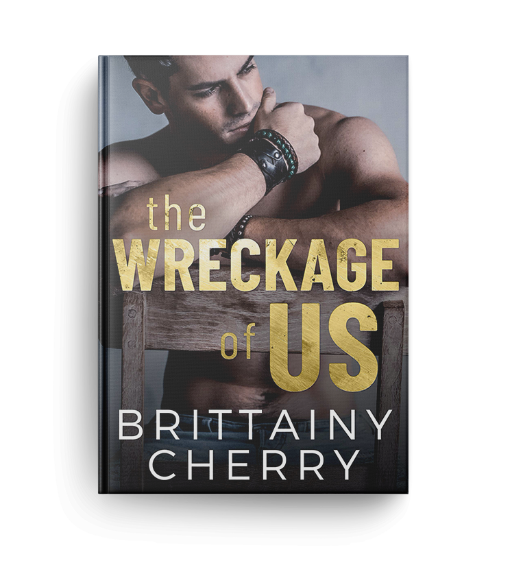 shirtless man resting on wooden chair and wearing black bracelets looks to the right on the cover of the wreckage of us by brittainy cherry