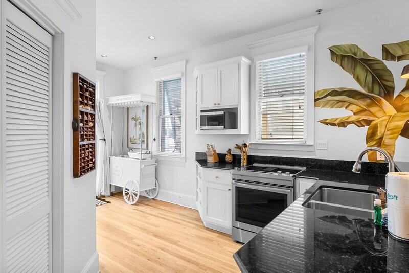 Cheerful kitchen with Salty Bottle cart and tropical banana leaf mural, located at The Florida House in downtown Carillon Beach, close to 30A and Santa Rosa Beach.