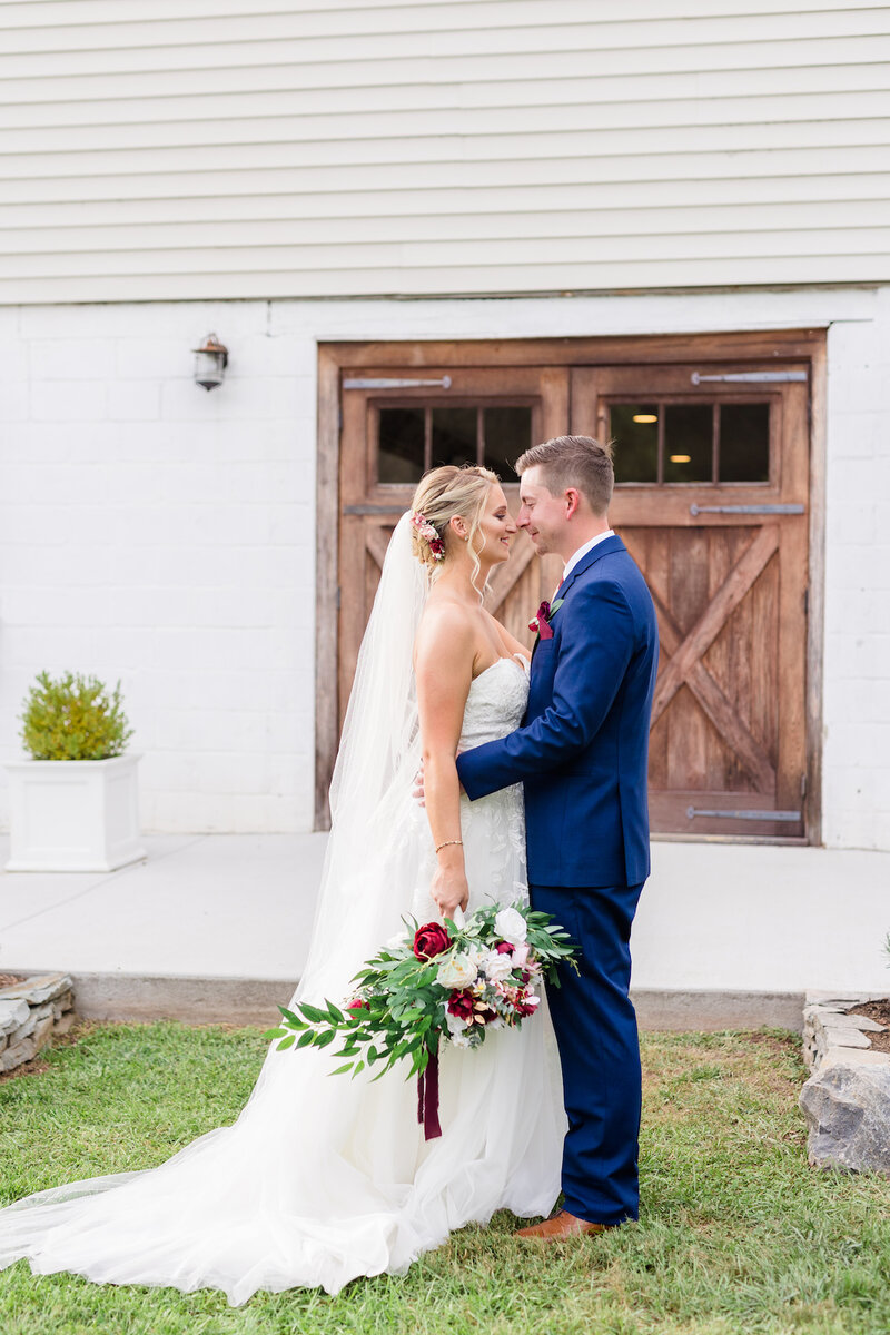 Bride and groom smiling outside rustic barn wedding venue