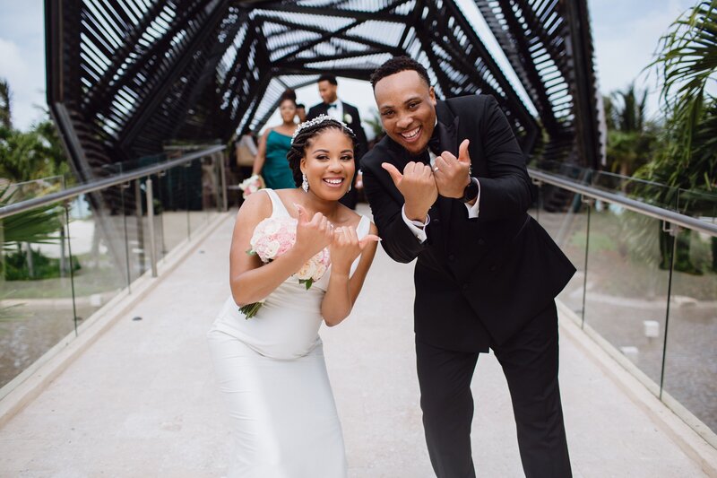 A bride and groom pose for a photo on a bridge.