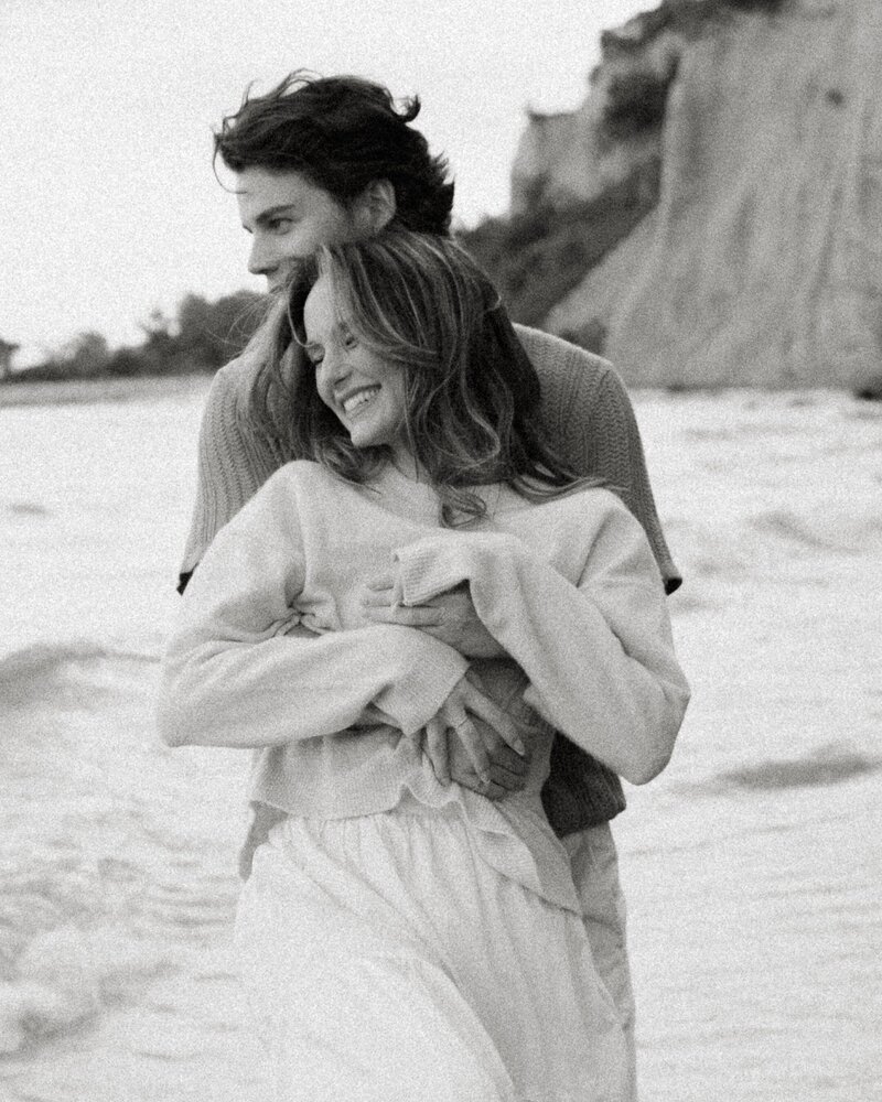 artistic portrait and man embracing woman in romantic portrait on beach at sunset in toronto, ontario