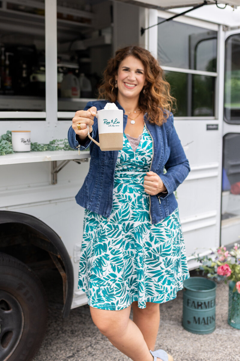 Rachel smiling while holding a cup of coffee with whipped cream on top