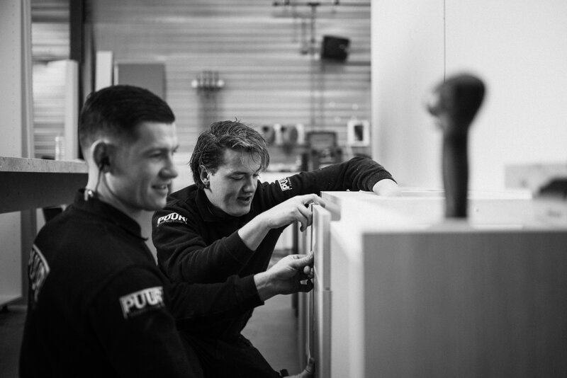 n het atelier van PUUR wordt met volle focus gewerkt aan de afwerking van een maatwerkmeubel. Twee vakmannen stemmen nauwkeurig af om elk detail perfect te krijgen.