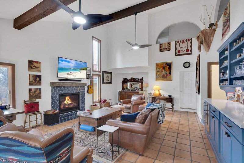 a cozy living room with a blue fireplace, leather couches, and an arched window.