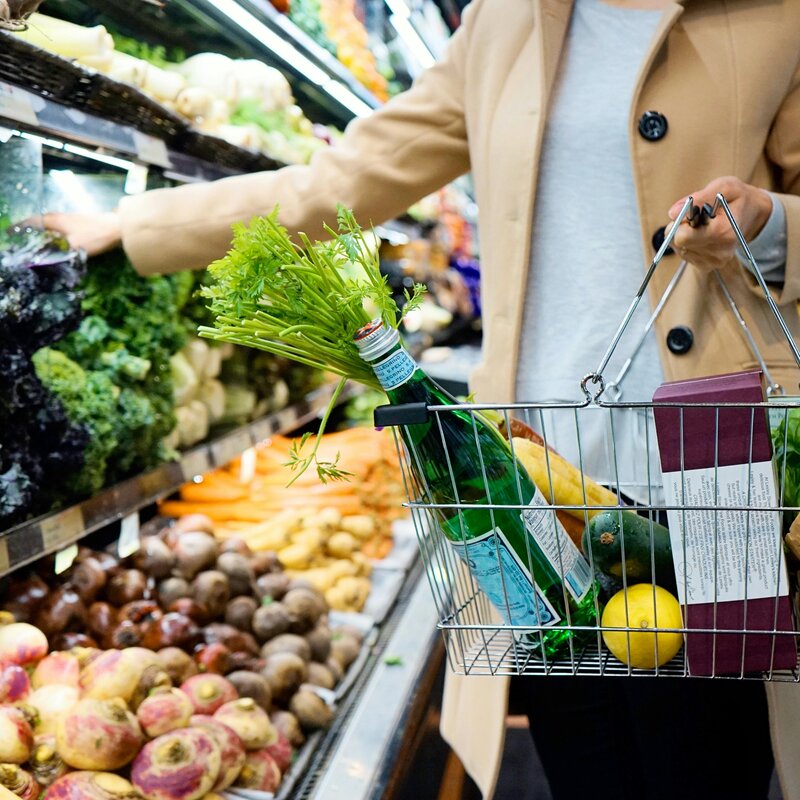 A woman shopping for groceries in a supermarket, selecting fresh produce from a display