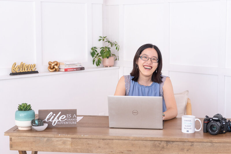 A woman smiling and sitting at her desk in her office.