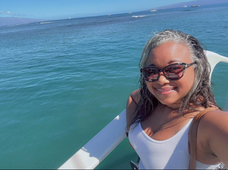 Letitia Hopkins smiling confidently while on a boat in Hawaii, embodying freedom, abundance, self-love, and Main Character Energy.