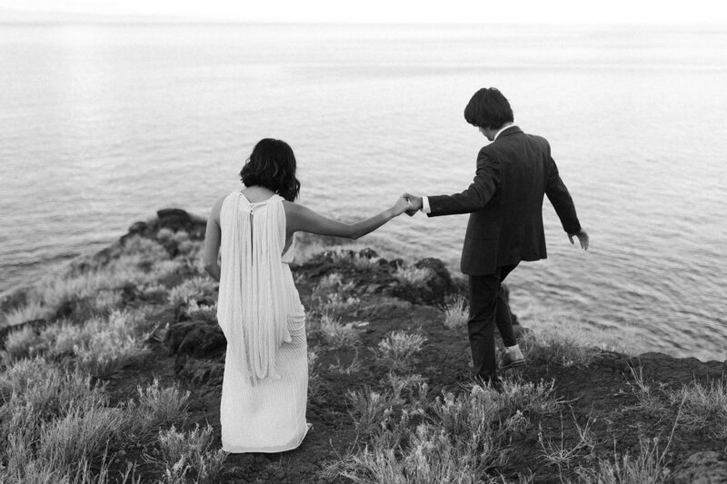 black and white image couple holding hands by lake