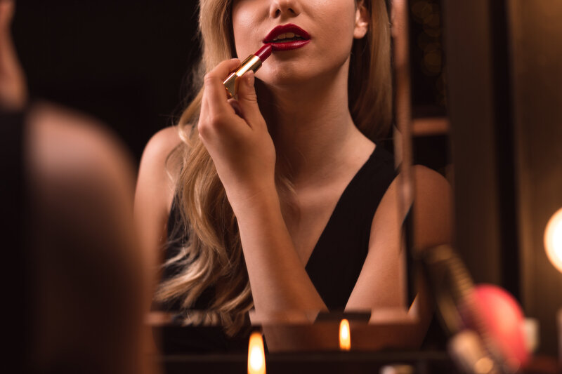 Woman in Evening Dress wearing Red Lipstick at a vanity mirror