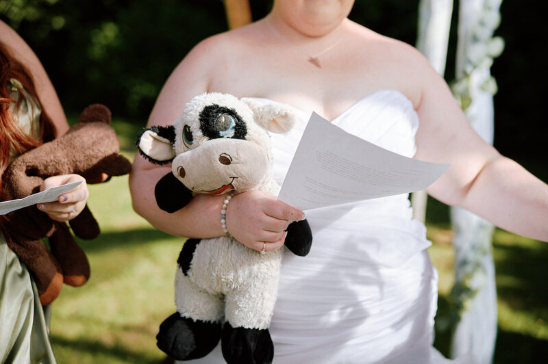 Bride reads her vows while holding a stuffed cow.