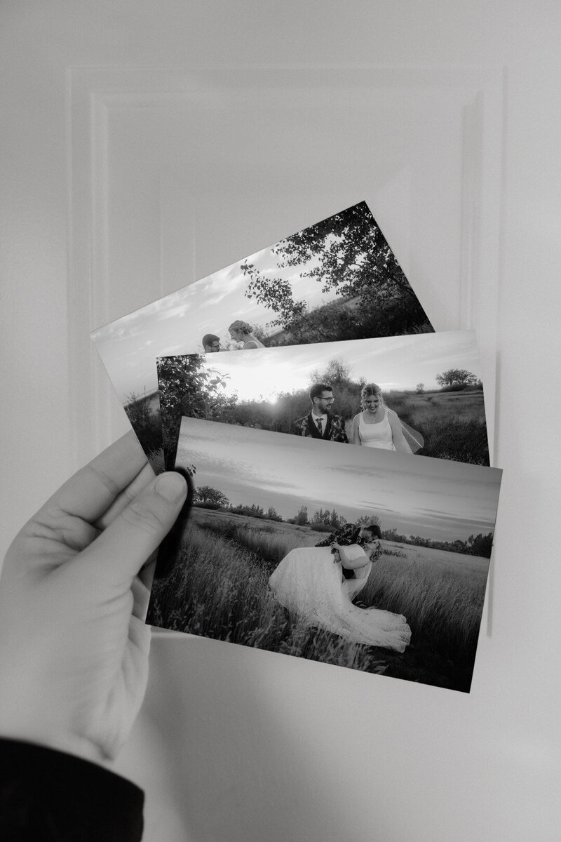 A person holds up 3 wedding prints.