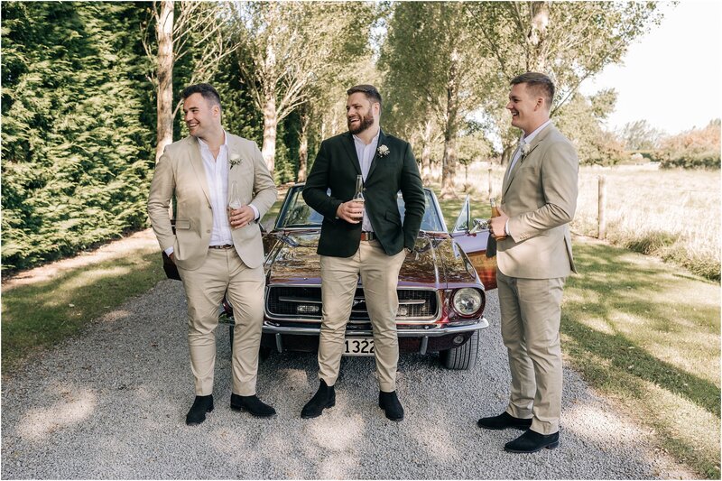 groom and groomsmen with convertible car on raod chinos and rm williams boots after wedding ceremony