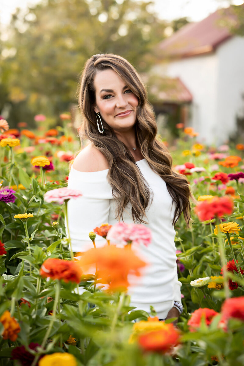 Image of Lindsey smiling while standing in a field of flowers.
