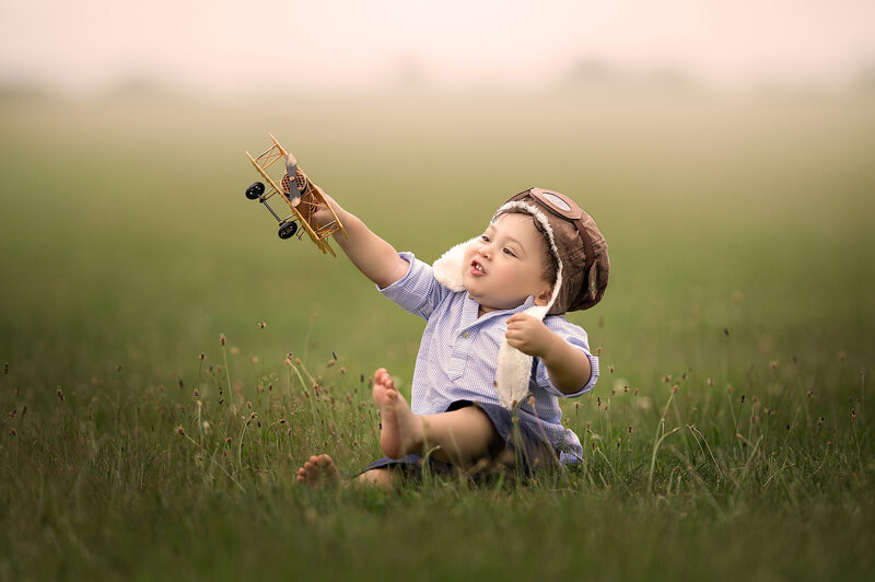 Photo of a toddler playing with a toy airplane on a park outside by Iya Estrellado.