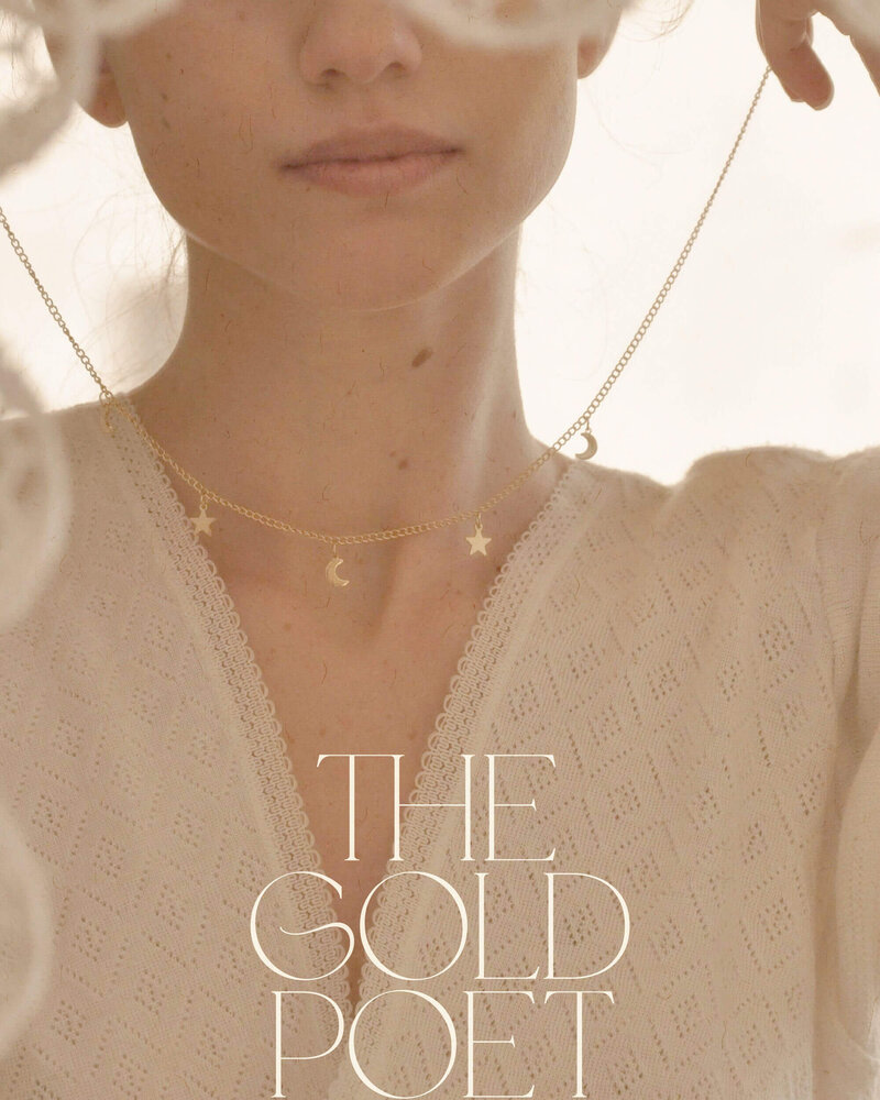 a woman putting on a gold necklace with star and moon shaped charms