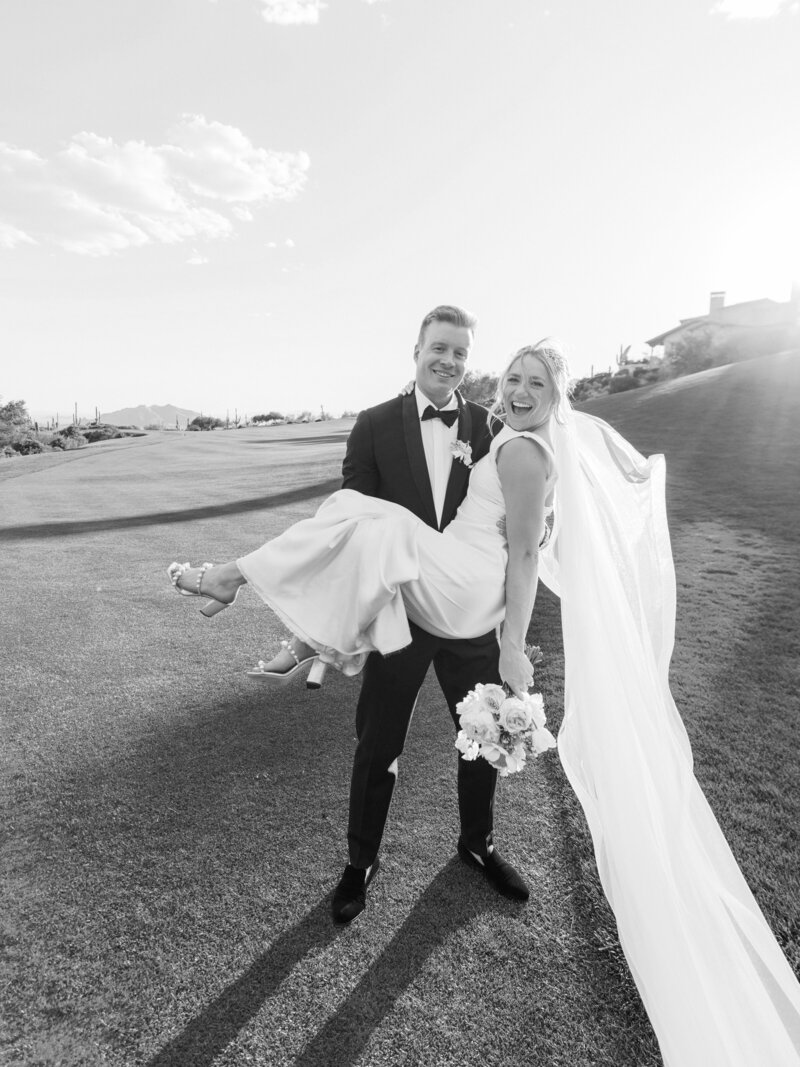 Best wedding photographer capturing an unforgettable wedding moment as the groom lifts his smiling bride at a breathtaking Arizona wedding.