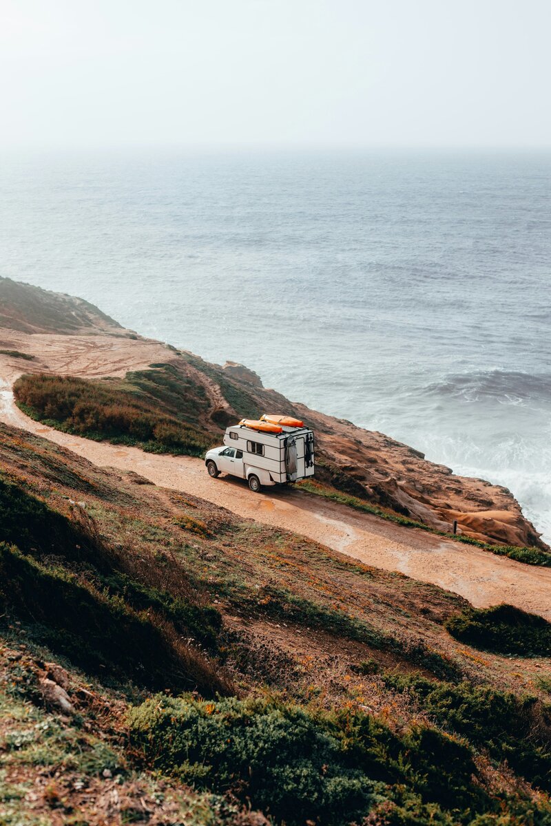 Camping-car sur un chemin côtier, avec la mer en fond