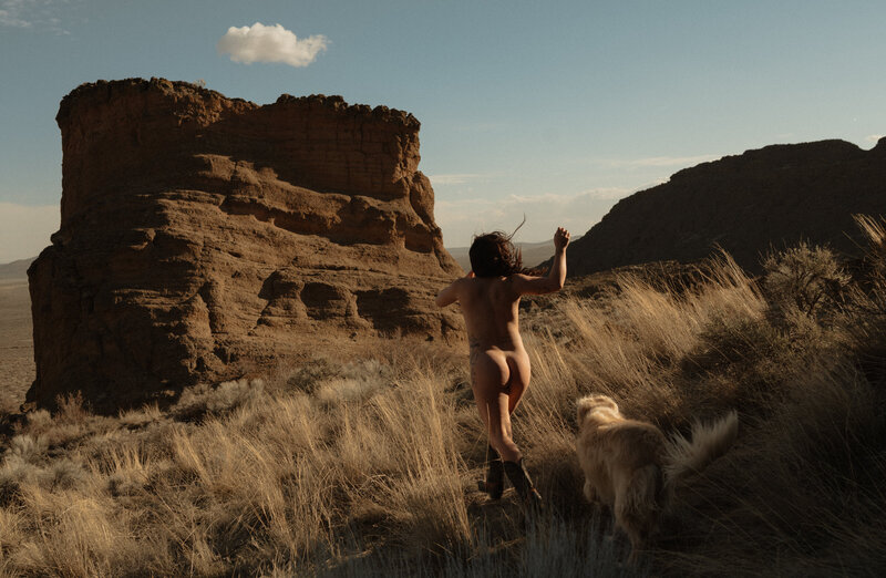 woman standing in the sun with her dog in the Moab, Utah desert on a sunny, warm day