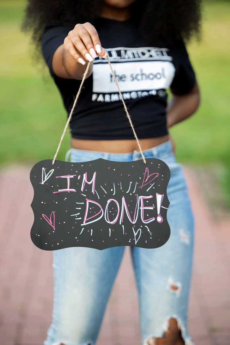Senior girl posing casually holding a "I'm Done" sign