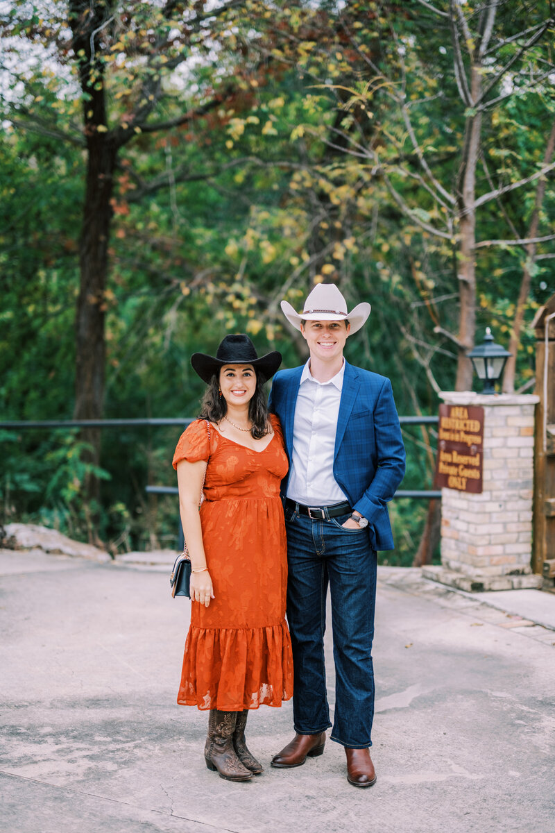 Portrait of a woman in a red dress and black cowboy hat and a man in a blue jacket with a white cowboy hat