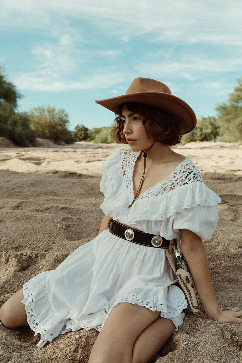 woman sitting on the ground wearing a cowboy hat