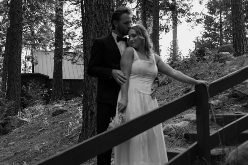 Blurry photo of groom hugging bride from behind, leaning on a staircase, in black and white.