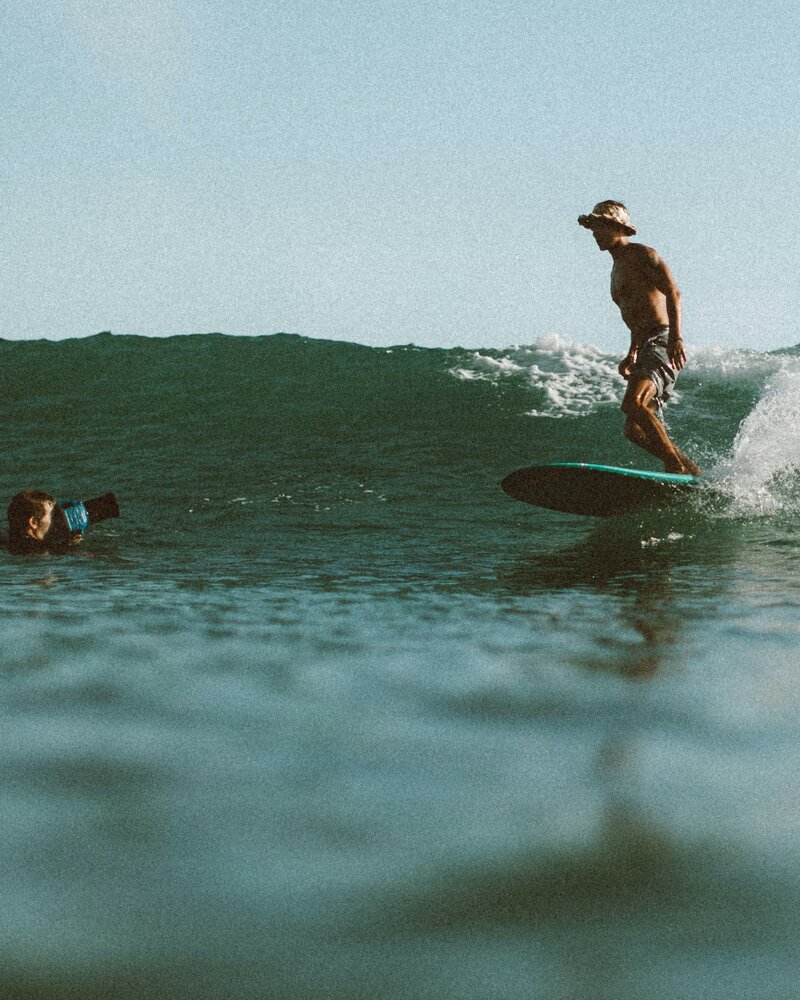 Man wearing a hat while surfing a small wave