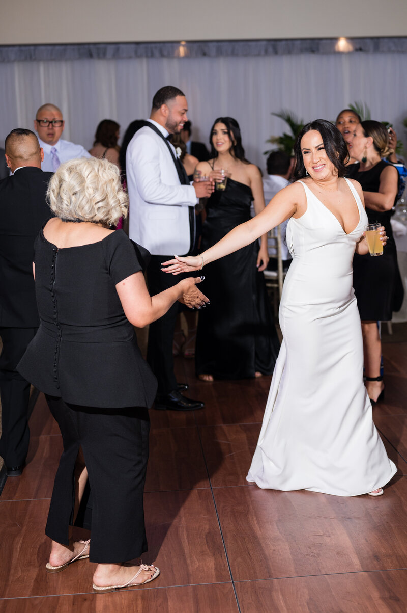 Bride dancing joyfully at the Emerald at Queensridge reception, surrounded by guests and glowing candlelight.
