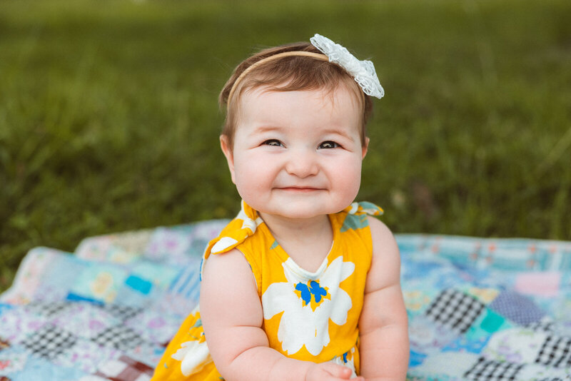 Headshot of a baby girl smiling at the camera. 