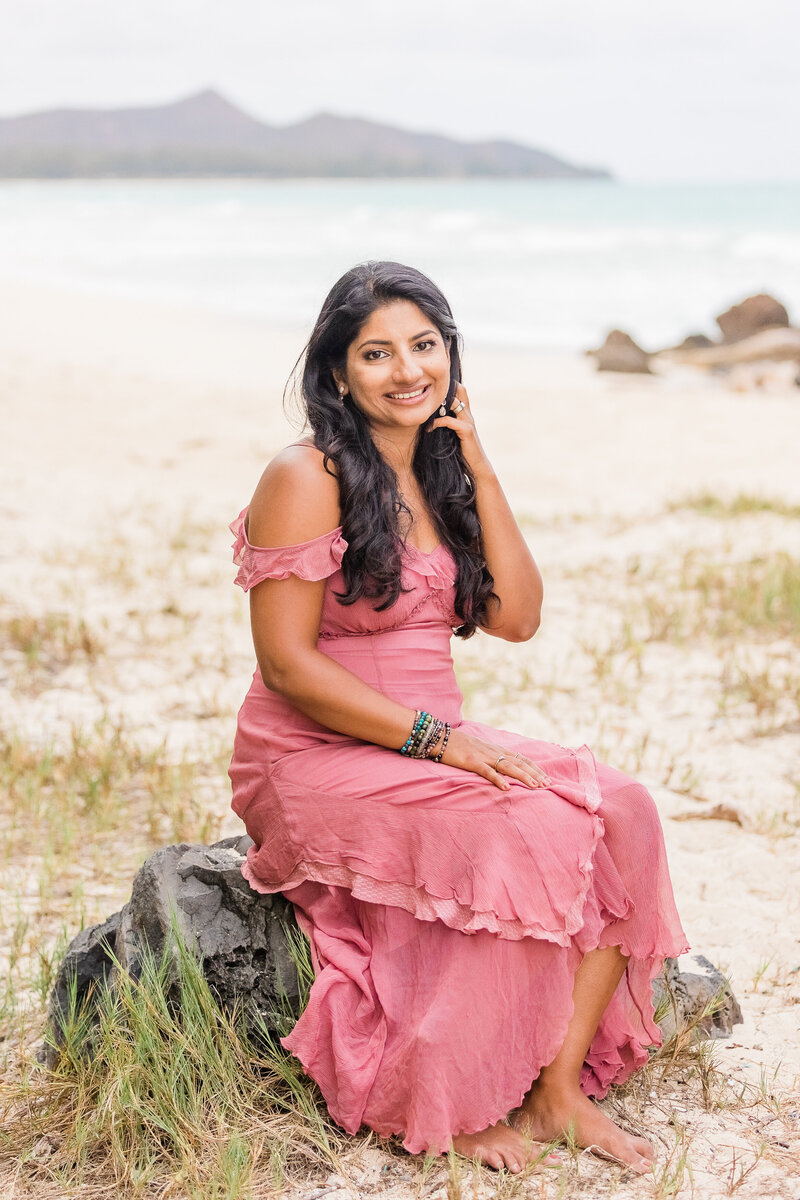 Life coach Radhika sitting on a rock on beach