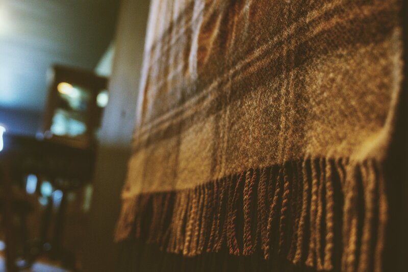 Wall with scottish woolen plaid knee blanket used as wall decoration heading up the stairs to open room area
