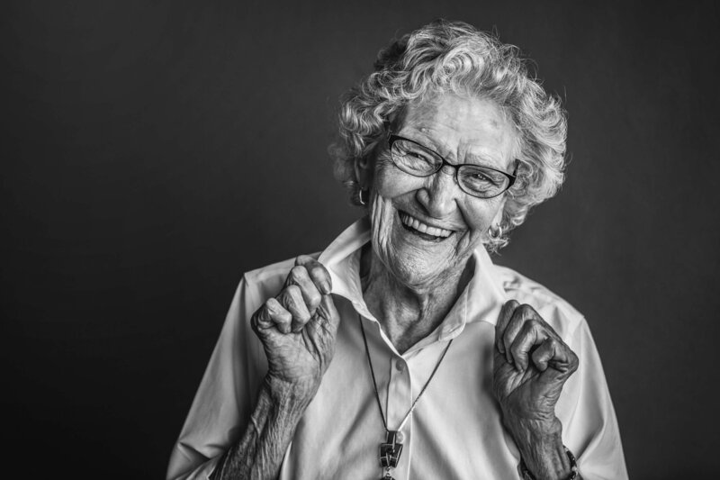 elderly woman laughs and adjusts her collar