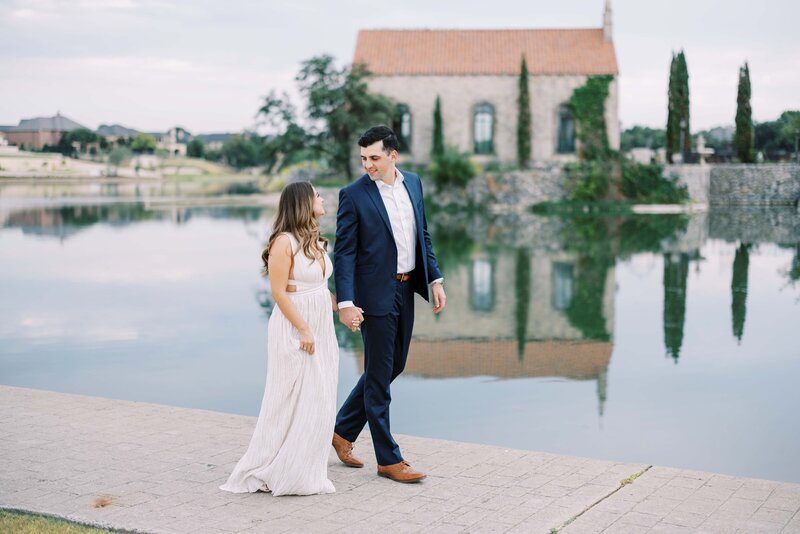 couple walking hand in hand at the adriatica village for their engagement session looking at each other