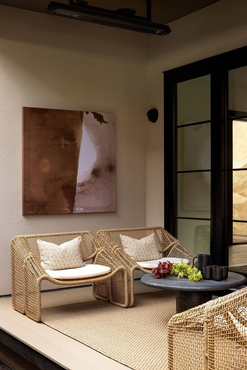 “Tranquil Japandi outdoor living area featuring a stone-clad fireplace, natural wood decking, oversized pendants, Sun Coast enclosure, and minimalist outdoor furniture.