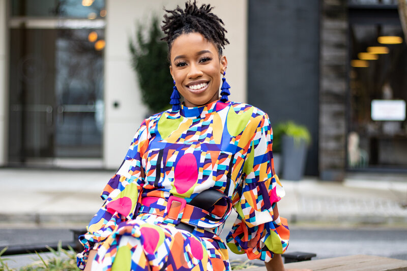 black woman sitting outside at table in colorful dress
