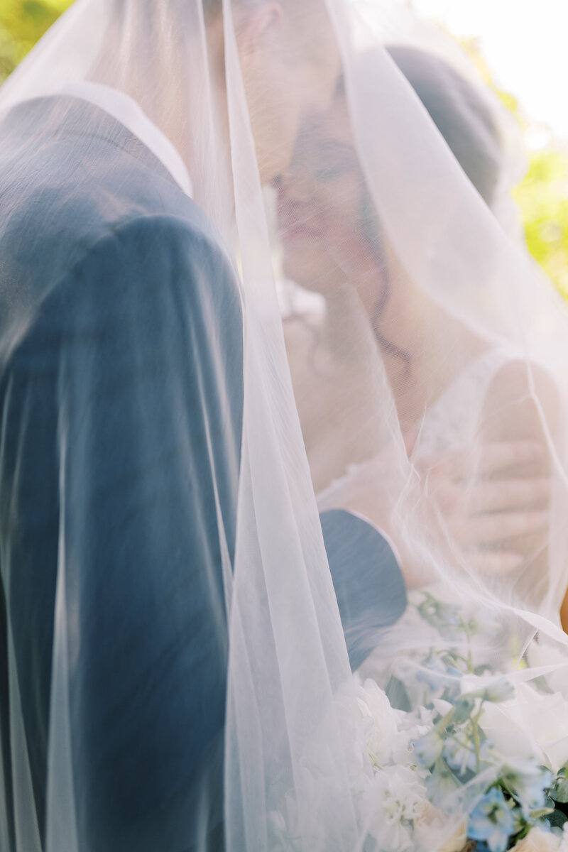 A bride and groom under a veil in a hazy romantic portrait