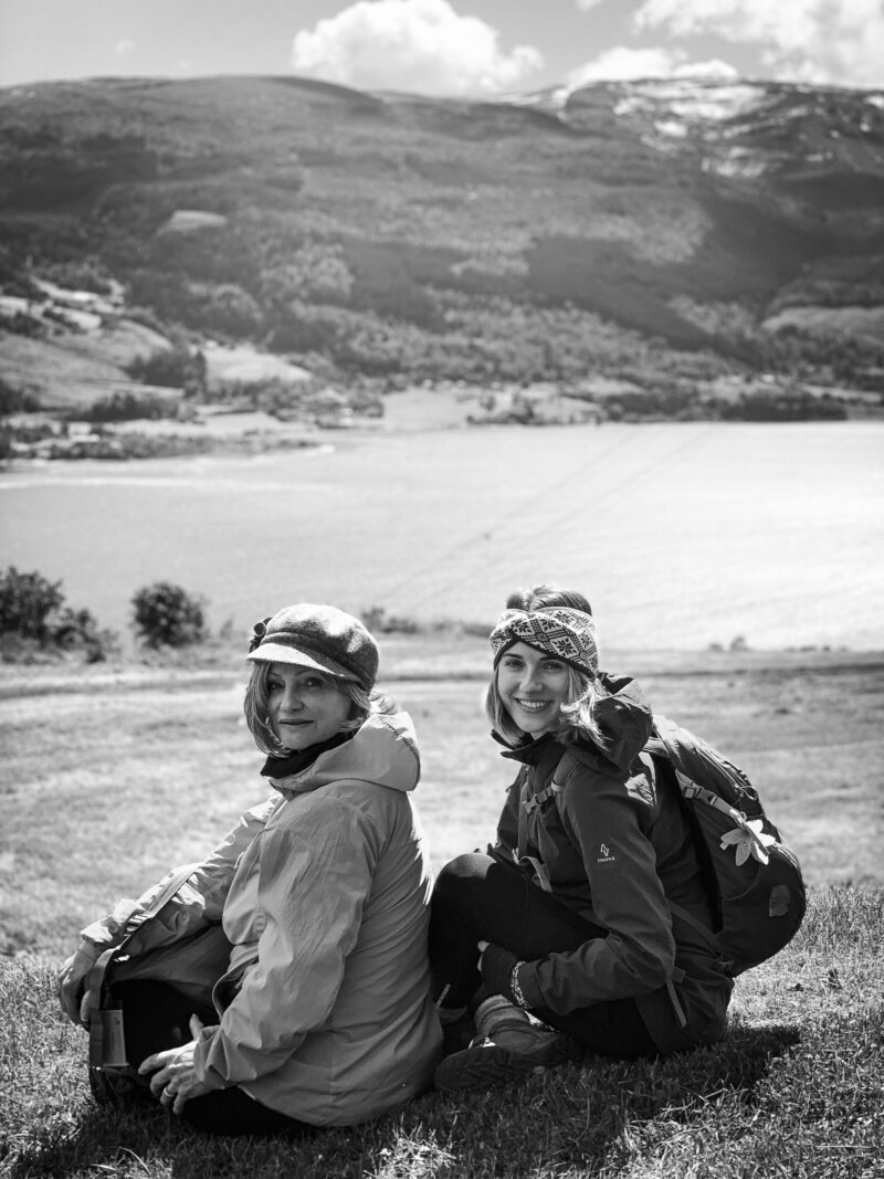 Black and white photo of two women sitting in front of a landscape turned around facing the camera