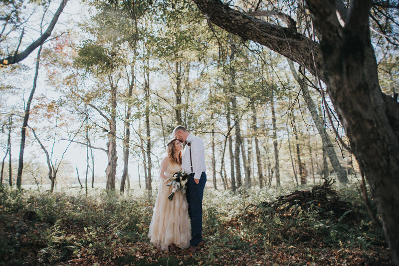 A bride and groom posing among tall trees